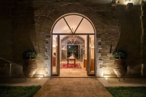 An arched entrance with a red rug leading to a table and chairs, flanked by potted plants. - Dimora Oru (Lecce)