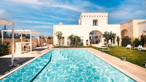 A swimming pool with a white building in the background. - Dimora Oru (Lecce)