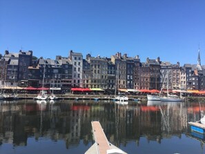 A waterfront view with a row of buildings, a dock, and several boats.
