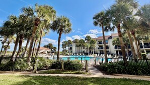 Ein Resort mit Schwimmbad, Palmen und einem mehrstöckigen Gebäude.