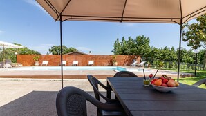 An outdoor patio with a table set for dining, a pool in the background, and a wooden fence enclosing the area. - Vacation Villa "La Quercia★ Swimming Pool-BBQ-Nature (Carbognano)