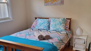 A bedroom with a wooden bed frame, a colorful quilt, and a 'relax' sign on the wall. - 5 min walk to the Beach! (Rosebud)