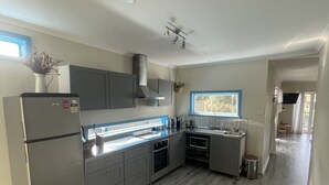 A modern kitchen with grey cabinets, stainless steel appliances, and a wooden floor. - 5 min walk to the Beach! (Rosebud)