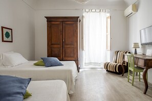 Un dormitorio con dos camas, un armario de madera, un escritorio con silla y una ventana con cortinas.