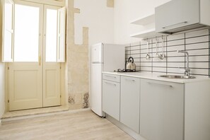 Een koelkast, kookgerei, borden en bestek, een eettafel