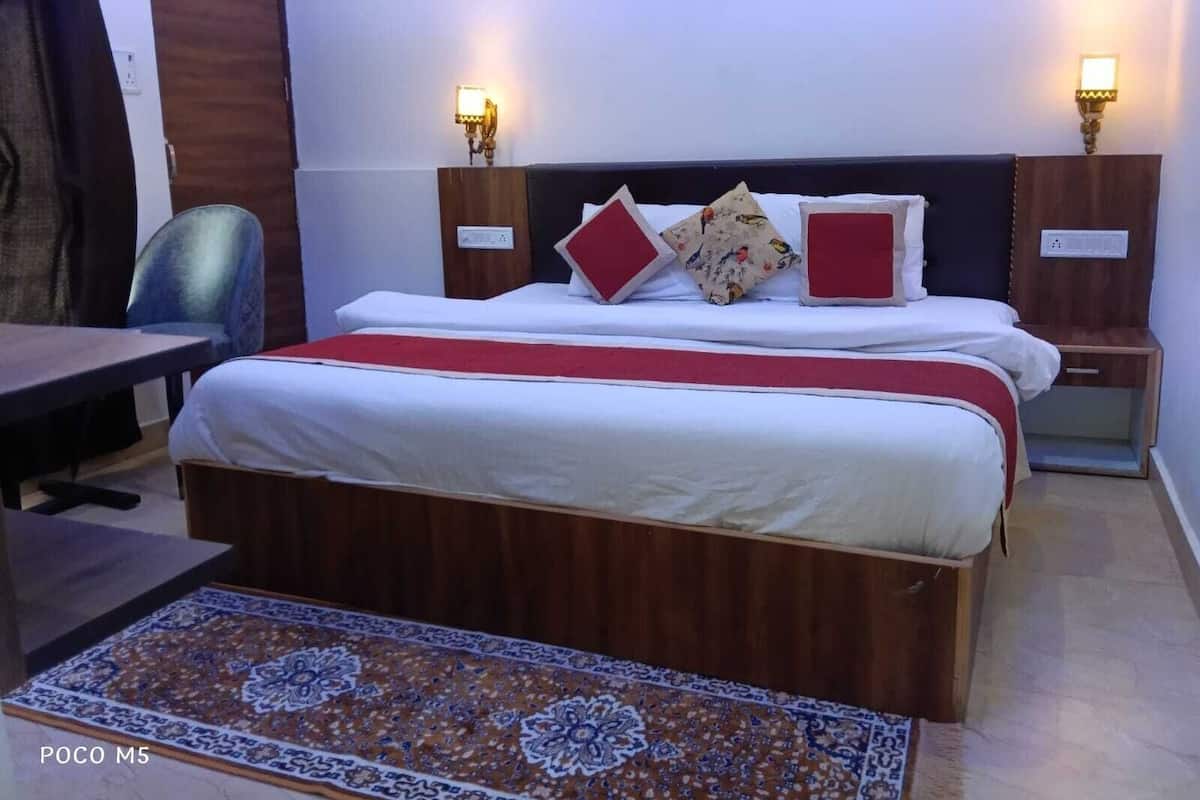 Habitació d'hotel amb un llit gran, dues taules de nit amb làmpades, un escriptori i una catifes amb dibuixos.
