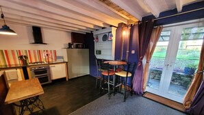 Eine kompakte Küche mit Essbereich, einem Gaskochfeld, einem Kühlschrank und einem kleinen Tisch mit Stühlen.