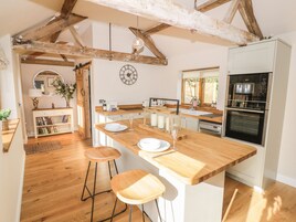 A kitchen with wooden countertops, a built-in oven, and a dining area with stools.