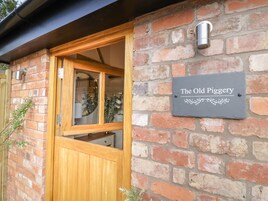 A brick wall with a wooden door and a sign reading "The Old Piggery."