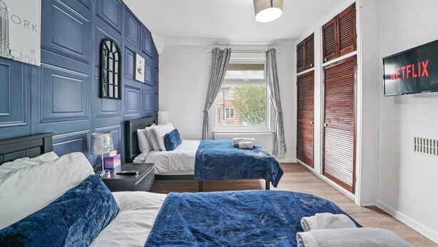 Une chambre d’hôtel avec deux lits, une télévision et une fenêtre avec des rideaux.