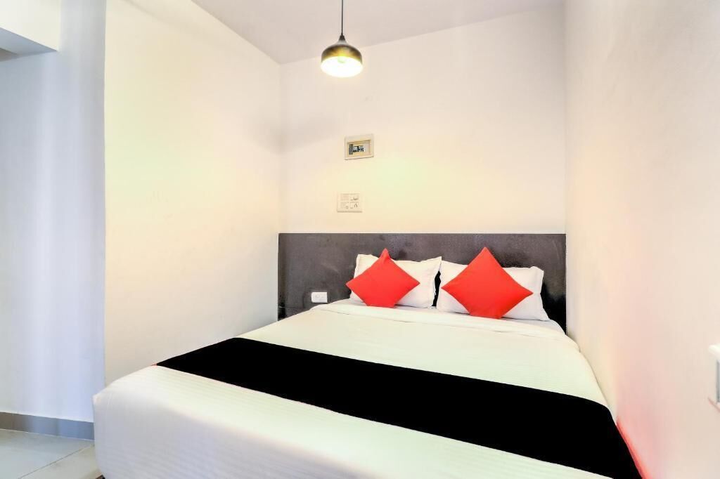 A hotel room with a bed, a headboard, and a hanging light fixture.