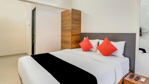 A modern hotel room with a large bed, a wooden accent wall, and a bedside table with a remote control. - Hotel Crystal Inn (Mumbai)