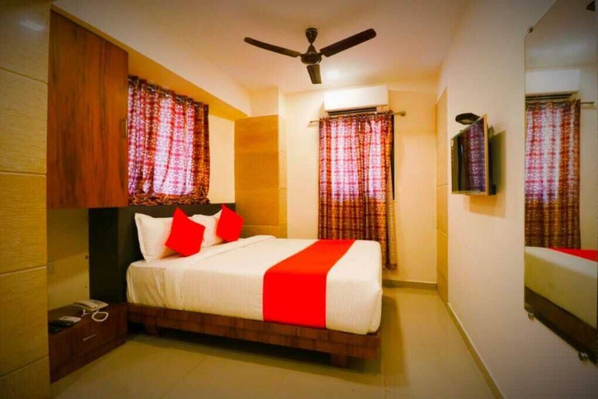 A bedroom with a bed, curtains, a ceiling fan, and a television on the wall.