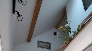 A modern kitchen with a stone wall, wooden beams, and a built-in stove. - House (Maupertus-sur-Mer)