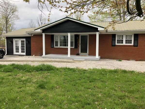 A two-story house with a covered porch, a brick exterior, and a front door. - Blue Holler’s back entrance is 2 driveways down, near Mammoth Cave and Nolin Lk (Mammoth Cave)