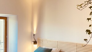 Une chambre avec deux lits, une tête de lit en bois, une lampe de chevet et une fenêtre avec des stores.