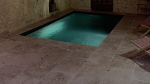 Une piscine intérieure avec des murs en pierre et un plafond en bois.