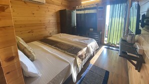 Una habitación de cabaña de madera con una cama, un escritorio y una ventana con cortinas.