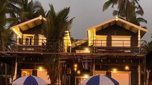 A two-story building with a balcony, wooden fence, and umbrellas. - Agonda Heritage (Canacona)