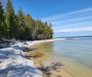 Una playa con agua cristalina, árboles y un litoral rocoso.