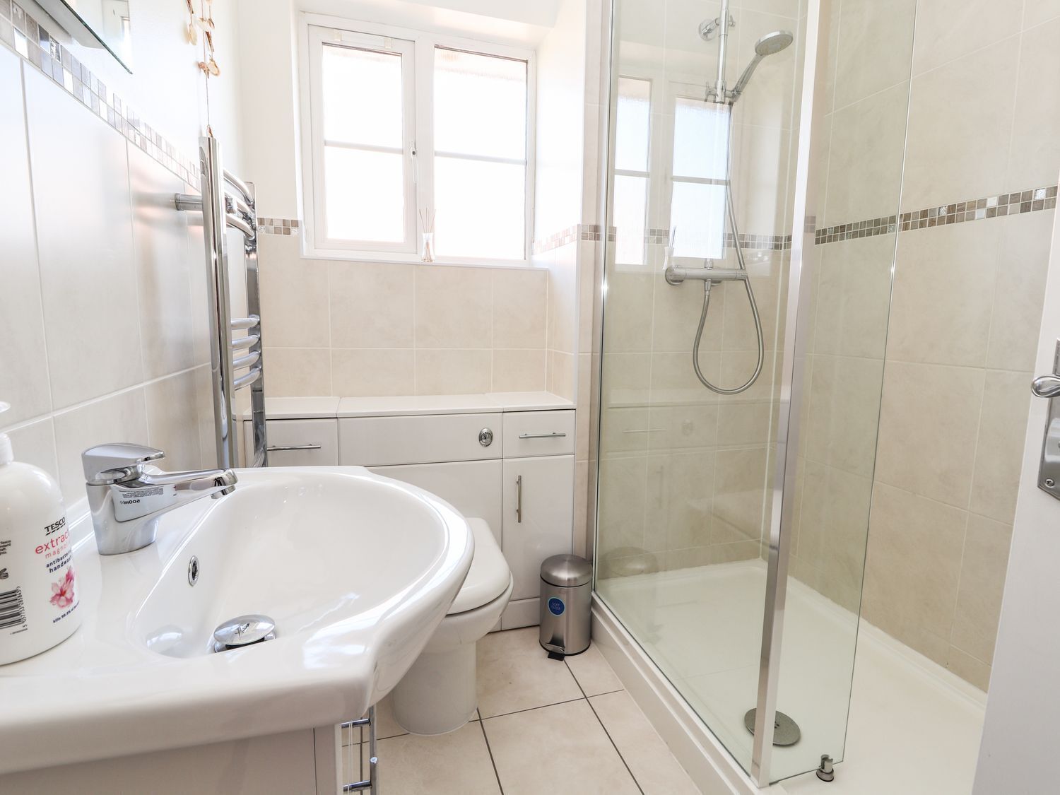 A modern bathroom with a white sink, toilet, and glass-enclosed shower.