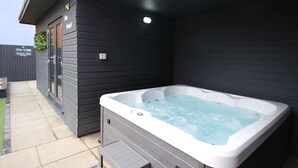 Ett bubbelbadkar placerat intill en byggnad med en skylt som visar vägen till stranden.