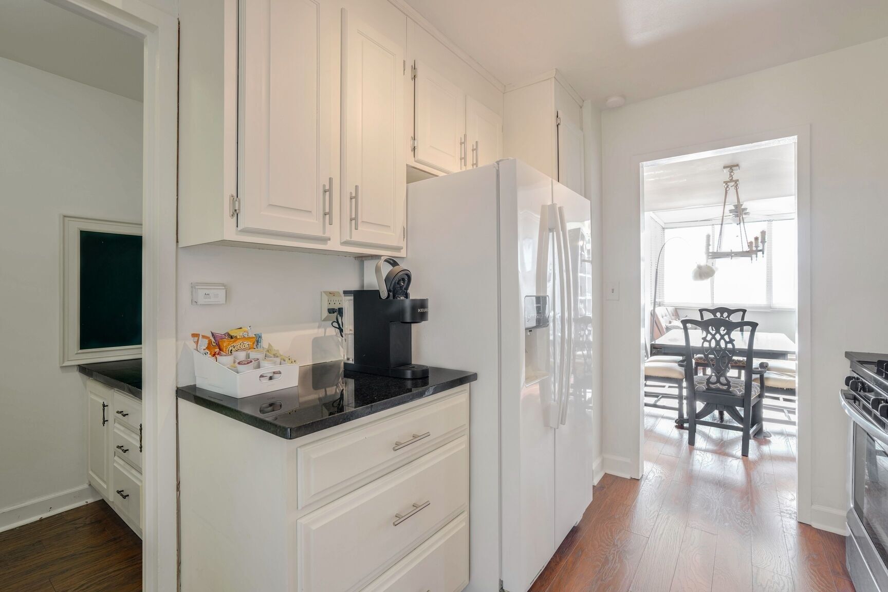 A modern kitchen with white cabinets, a black countertop, and a built-in coffee maker.