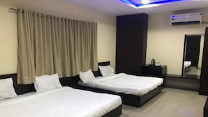 A hotel room with two beds, a dark headboard, a bedside table, a mirror, and an air conditioning unit. - Hotel Imperial Udaipur (Udaipur)
