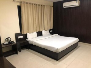 A modern hotel room with a large bed, a bedside table with a kettle, and a wall-mounted air conditioner. - Hotel Imperial Udaipur (Udaipur)