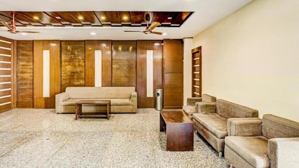 A modern living room with a sofa, two armchairs, and a coffee table. The room features a wooden accent wall and a ceiling fan. - Hotel Imperial Udaipur (Udaipur)