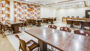 A conference room with multiple tables and chairs, a patterned wall, and ceiling fans. - Hotel Imperial Udaipur (Udaipur)