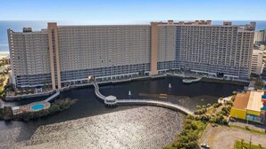 A large hotel with multiple floors, a central courtyard with a pool, and a view of the ocean. - Laketown Wharf 822- 2BR, Oceanview (Panama City Beach)