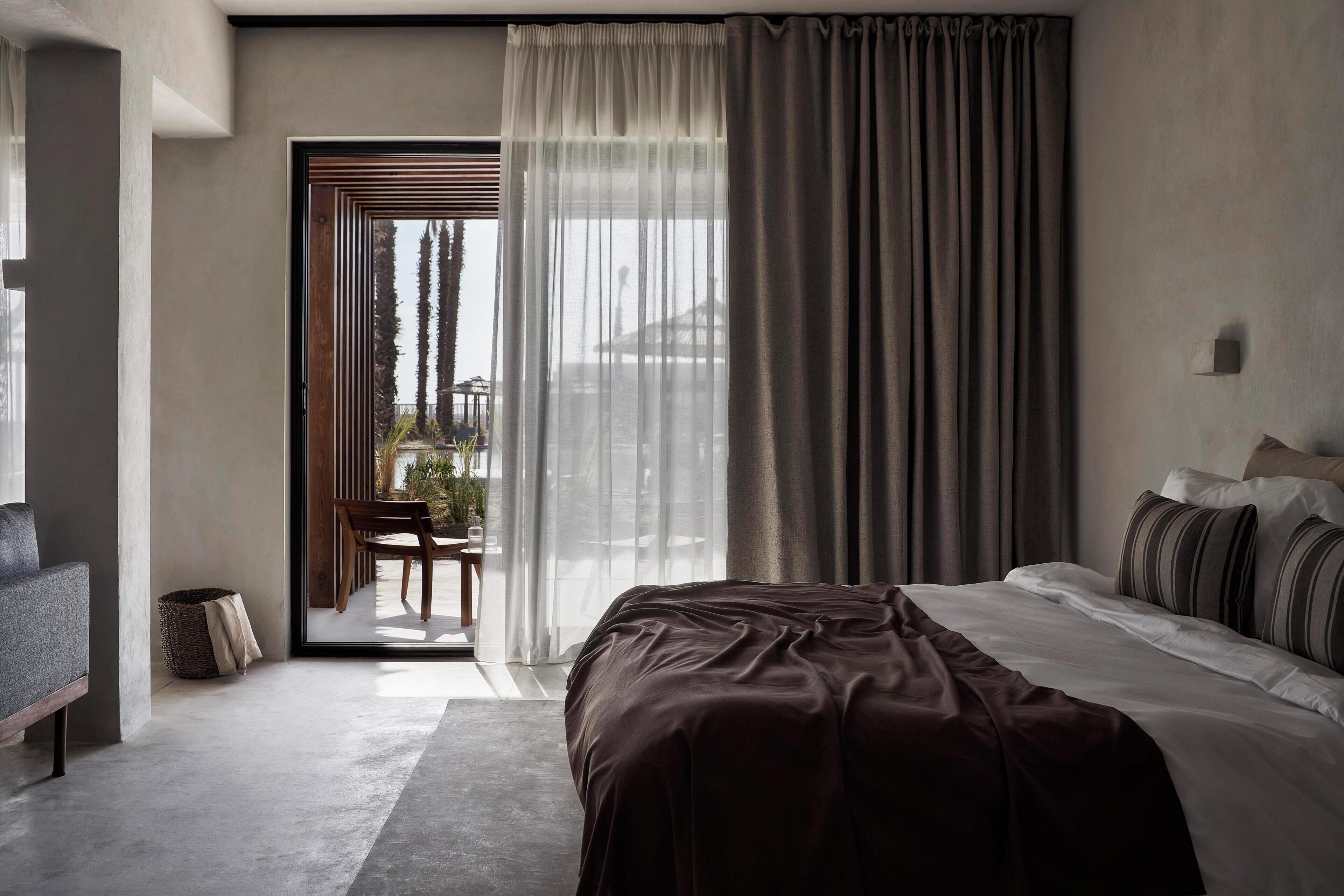 Une chambre à coucher moderne, dotée d’un grand lit, d’un canapé et offrant une vue sur l’extérieur grâce à une porte coulissante.