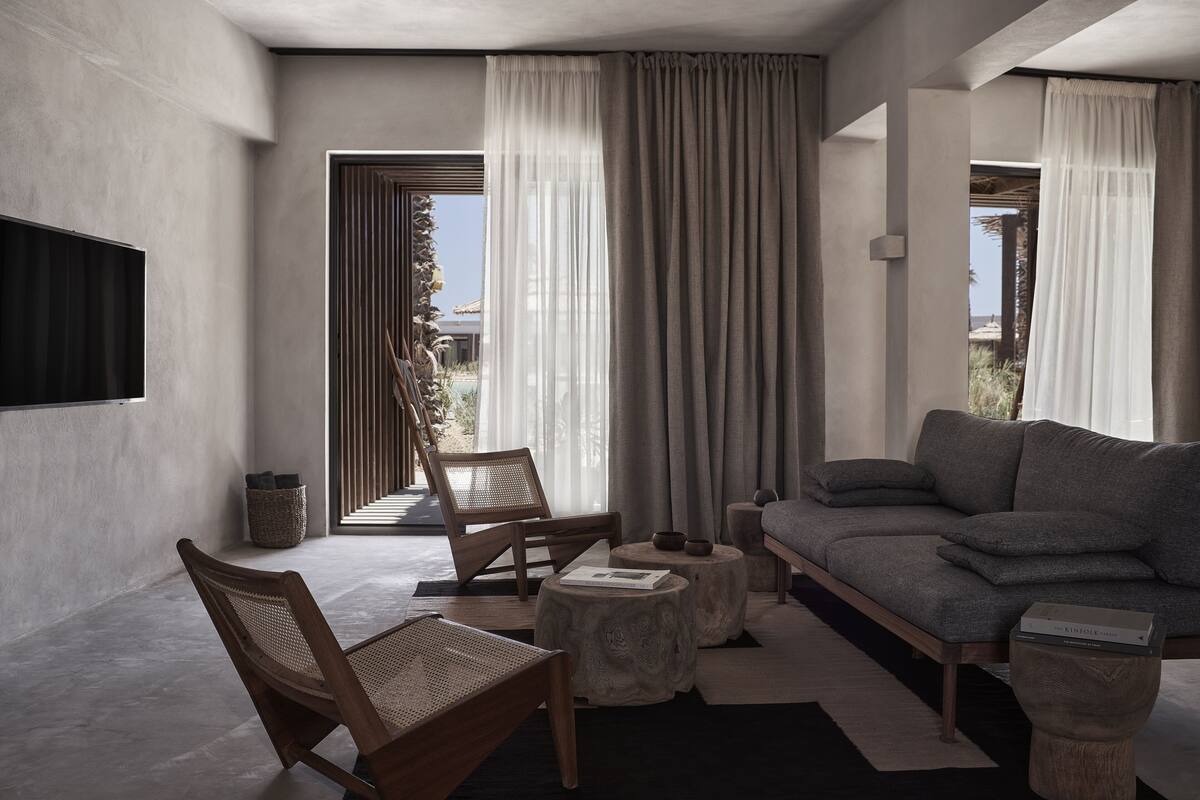 A modern living room with a sofa, two chairs, a coffee table, and a TV.