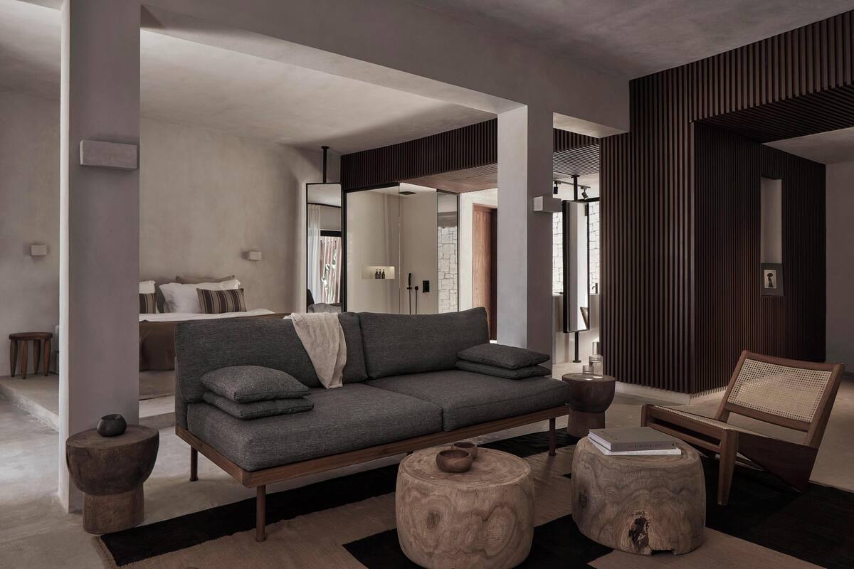 A modern living room with a grey sofa, wooden side tables, and a woven chair.