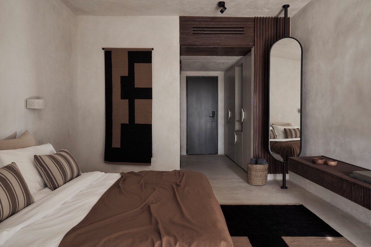 A modern bedroom with a bed, a large mirror, and a wardrobe.