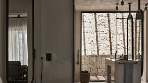 A modern bathroom with a stone wall, a large mirror, and a sink with a towel hanging on the wall. - Casa Cook North Coast -  Adults only (El Alamein)