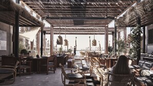 An outdoor dining area with wicker furniture, thatched roof, and potted plants. - Casa Cook North Coast -  Adults only (El Alamein)