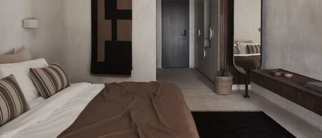 Quarto de hotel moderno com uma cama, um espelho grande, um guarda-roupa e uma porta que dá para outro quarto.