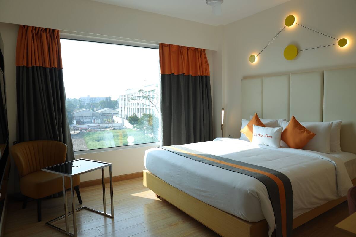 Habitación de hotel con una cama grande, un escritorio y vistas a un paisaje urbano.
