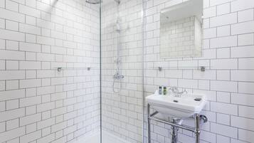 A modern bathroom with white subway tiles, a glass-enclosed shower, and a white sink with chrome fixtures.