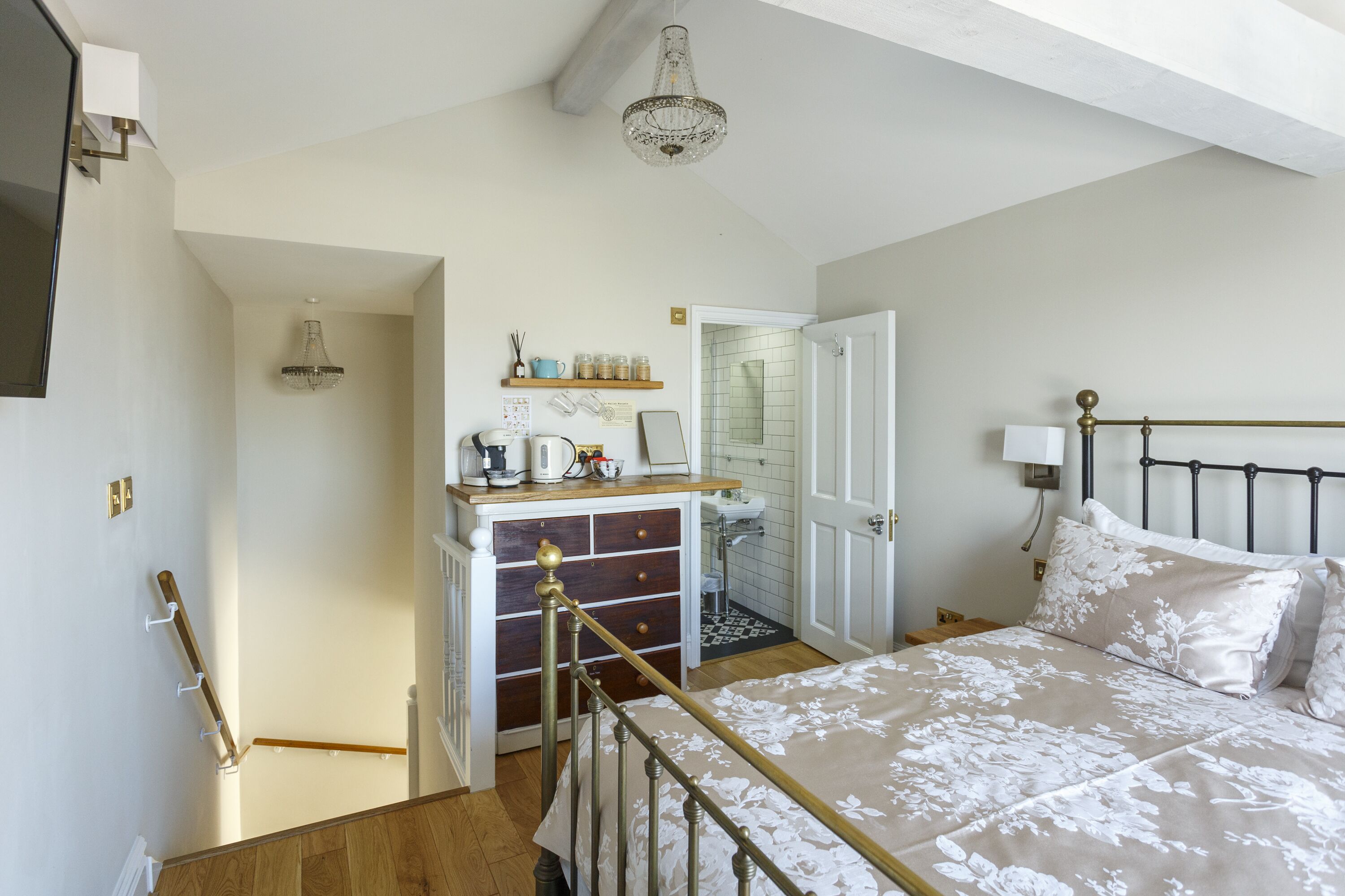 A bedroom with a bed, bedside table, and a small kitchenette area.