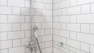A shower with a handheld showerhead and a wall-mounted faucet.