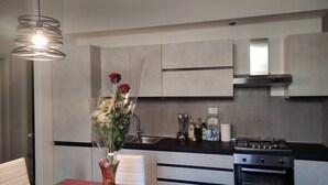 A modern kitchen with a dining table, a vase of flowers, and a stove. - VACATION HOME RICKY-LERUA (Firenze)