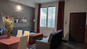 A modern living room with a dining area, a large window with curtains, a wall-mounted artwork, and a door. - VACATION HOME RICKY-LERUA (Firenze)