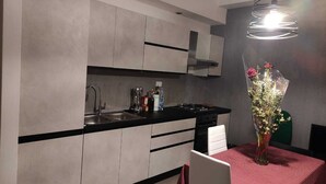 A modern kitchen with a black countertop, stainless steel sink, and a vase of flowers on the dining table. - VACATION HOME RICKY-LERUA (Firenze)