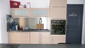 A modern kitchen with light wood cabinets, a stainless steel sink, and an oven. - Spacious and quiet house (LA FRESNAIS)