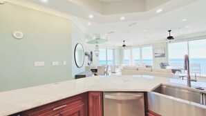 A modern kitchen with a large island, stainless steel appliances, and a view to the outside.