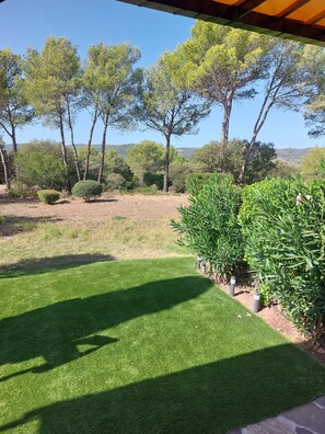 A well-maintained garden with a lawn, various shrubs, and trees, viewed from a covered area. - Villa Golf Saint Endréol La Motte (La Motte)
