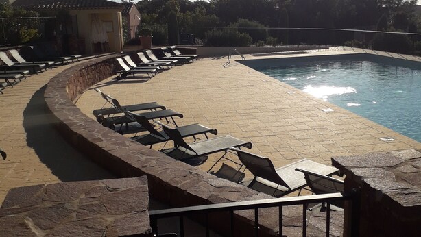 A poolside area with lounge chairs and a stone wall. - Villa Golf Saint Endréol La Motte (La Motte)